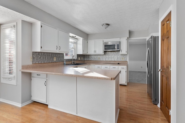 kitchen with white cabinets, stainless steel appliances, light hardwood / wood-style flooring, and sink