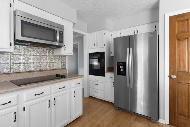 kitchen with black appliances, white cabinets, light wood-type flooring, a textured ceiling, and tasteful backsplash