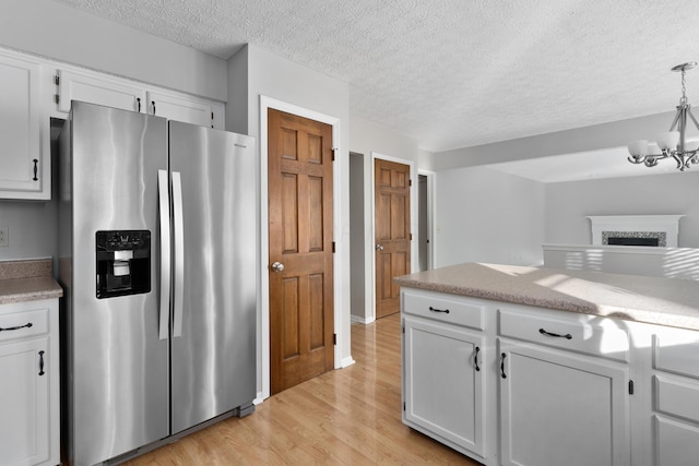 kitchen with hanging light fixtures, a notable chandelier, stainless steel fridge, white cabinets, and light wood-type flooring