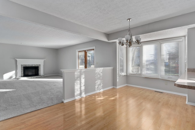 unfurnished dining area with a textured ceiling, light hardwood / wood-style flooring, and a notable chandelier