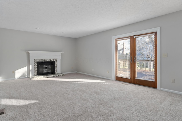 unfurnished living room featuring french doors, light colored carpet, and a textured ceiling