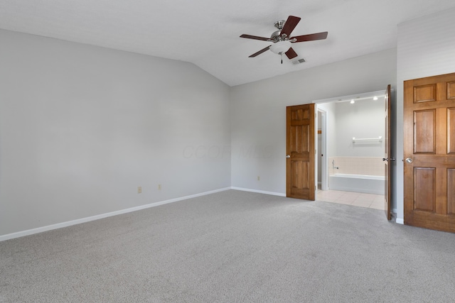 unfurnished bedroom with ceiling fan, light colored carpet, ensuite bathroom, and vaulted ceiling