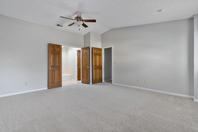 unfurnished bedroom with lofted ceiling, ensuite bathroom, ceiling fan, a textured ceiling, and light colored carpet