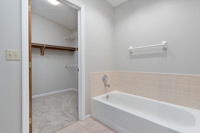 bathroom with a tub, tile patterned flooring, and a textured ceiling