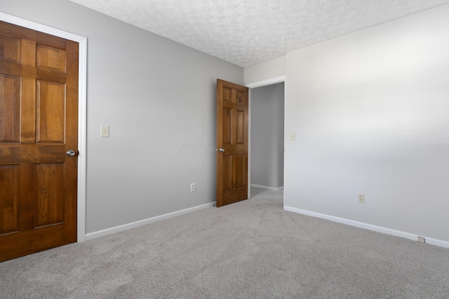 spare room with a textured ceiling and light carpet