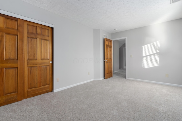 unfurnished bedroom featuring light colored carpet and a textured ceiling