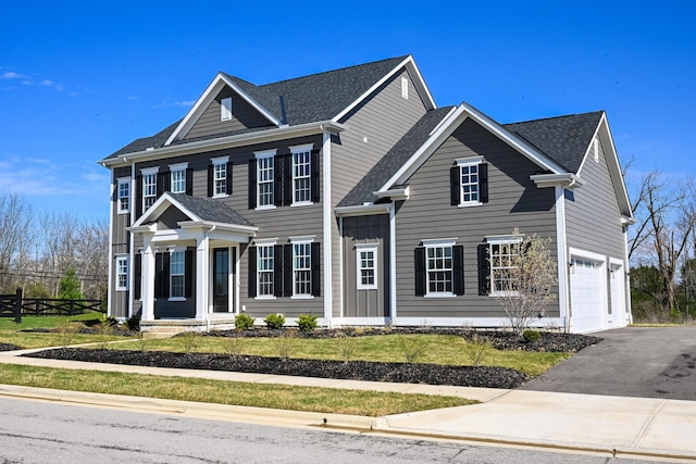 view of front of house with roof with shingles, fence, a garage, and aphalt driveway