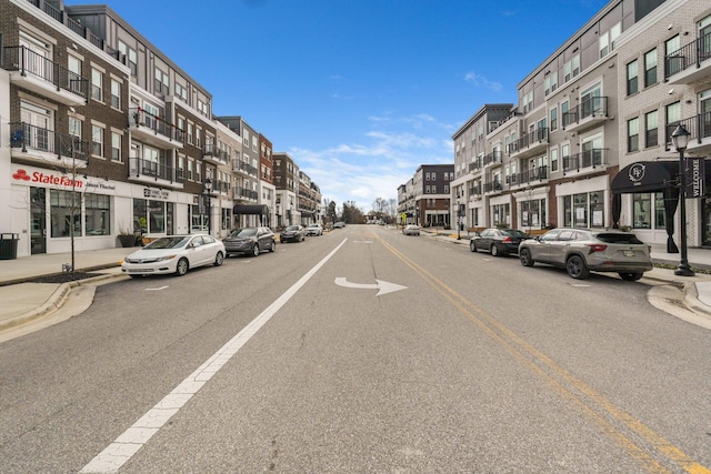 view of street featuring street lights, curbs, and sidewalks