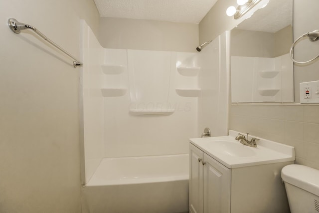 full bathroom featuring shower / bathing tub combination, vanity, toilet, a textured ceiling, and tile walls