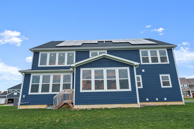 rear view of house featuring a lawn and solar panels