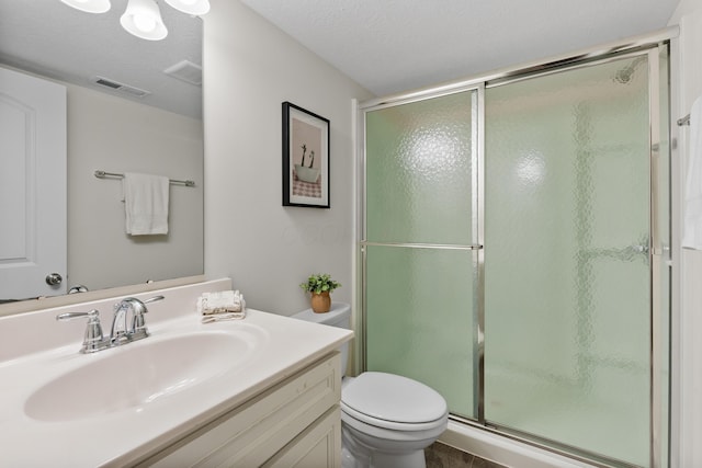 bathroom with a shower with door, vanity, a textured ceiling, and toilet