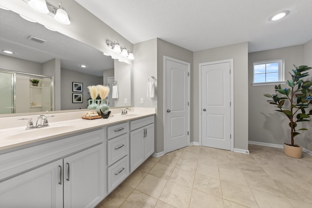 bathroom with tile patterned floors, vanity, a shower with shower door, and a textured ceiling