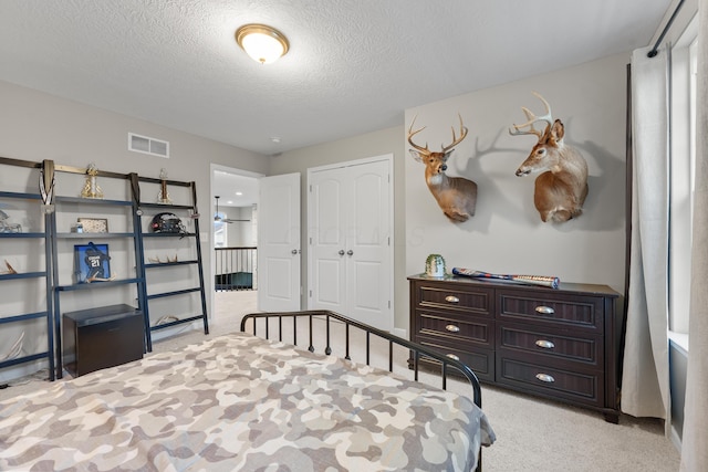 carpeted bedroom featuring a textured ceiling and a closet