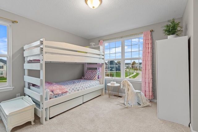 bedroom featuring carpet, a textured ceiling, and multiple windows