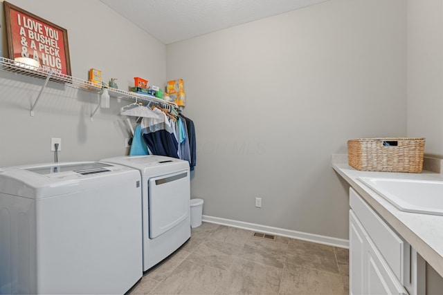 laundry room featuring sink, washer and dryer, and a textured ceiling