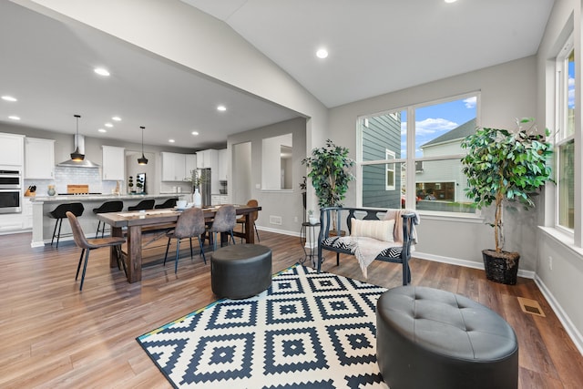 living room with light wood-type flooring and vaulted ceiling