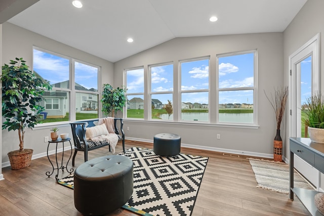 living area with a water view, lofted ceiling, and light wood-type flooring