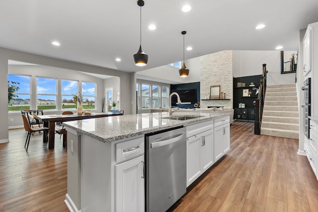 kitchen featuring sink, light hardwood / wood-style flooring, dishwasher, white cabinetry, and an island with sink