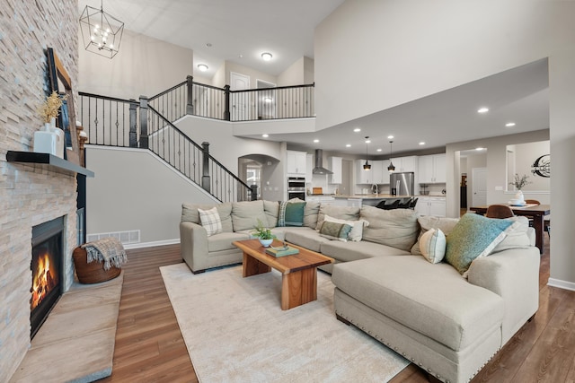 living room with a fireplace, light hardwood / wood-style flooring, a high ceiling, and an inviting chandelier