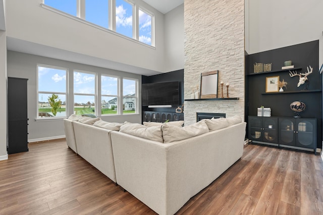 living room with hardwood / wood-style flooring, a fireplace, and a high ceiling