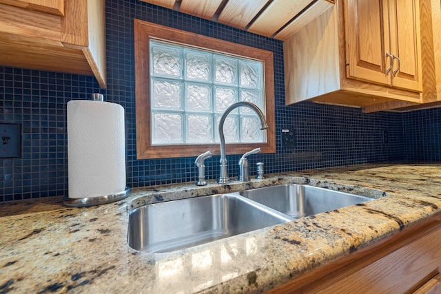 kitchen with decorative backsplash, sink, light stone countertops, and tile walls