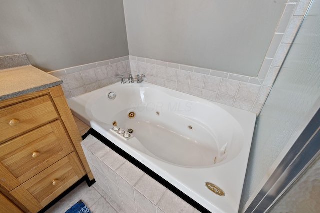 bathroom featuring tile patterned flooring, vanity, and tiled tub