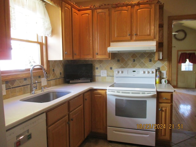 kitchen with decorative backsplash, white appliances, and sink