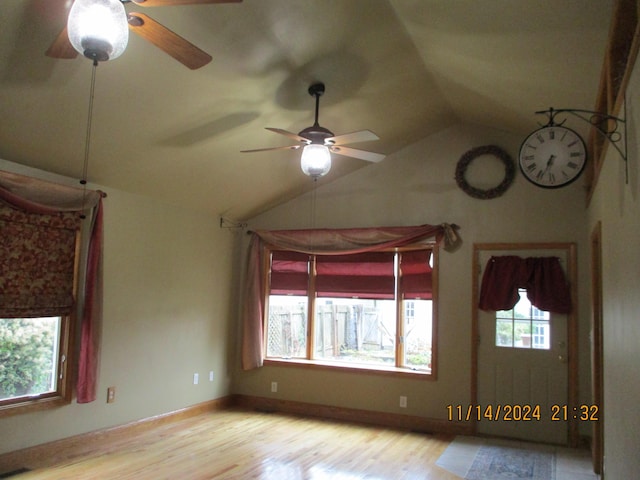 spare room with light hardwood / wood-style floors, a wealth of natural light, lofted ceiling, and ceiling fan