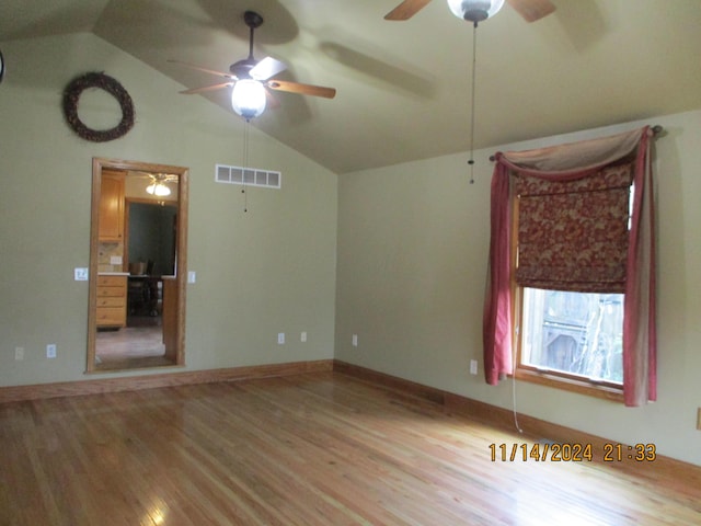 empty room with ceiling fan, hardwood / wood-style floors, and lofted ceiling