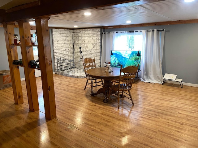 dining room featuring light wood-type flooring and brick wall