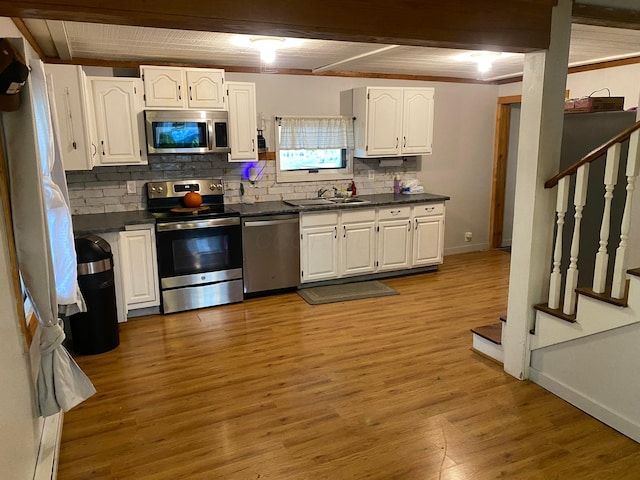 kitchen featuring appliances with stainless steel finishes, backsplash, sink, light hardwood / wood-style flooring, and white cabinetry