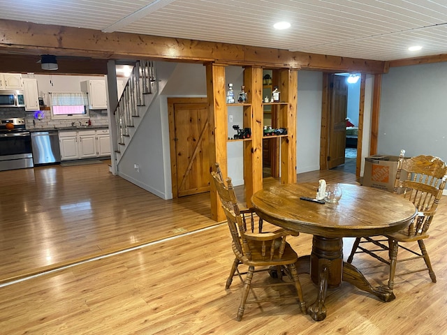 dining room with beamed ceiling, light wood-type flooring, and wood ceiling