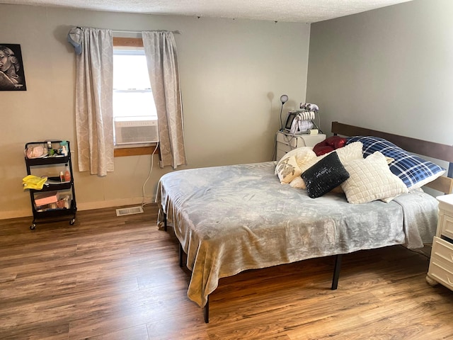 bedroom with a textured ceiling, light hardwood / wood-style floors, and cooling unit