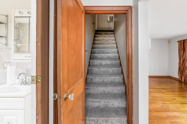 staircase featuring hardwood / wood-style floors and sink