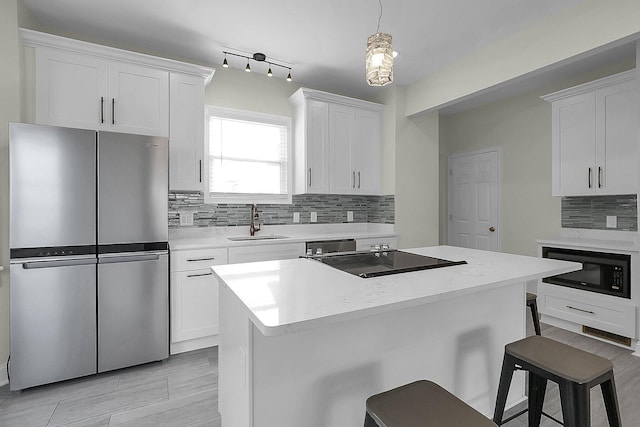 kitchen with pendant lighting, sink, white cabinetry, and black appliances