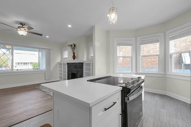 kitchen featuring a wealth of natural light, light hardwood / wood-style floors, stainless steel electric stove, and pendant lighting