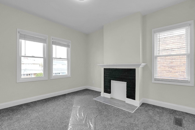 unfurnished living room with a fireplace and dark colored carpet