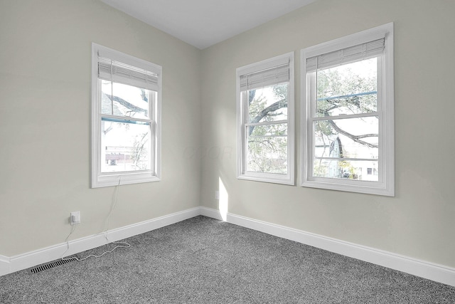 unfurnished room with dark carpet and a wealth of natural light