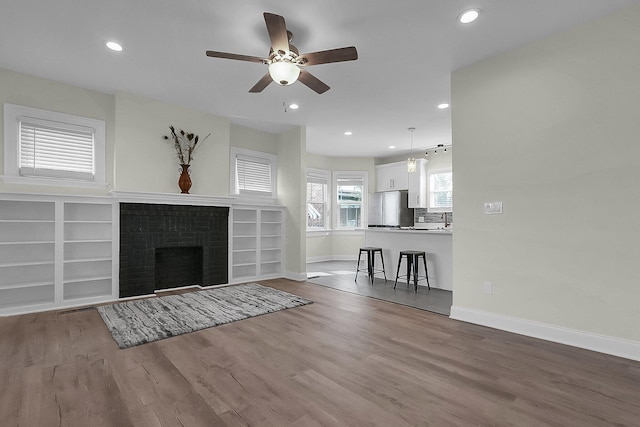 unfurnished living room featuring ceiling fan, a fireplace, and hardwood / wood-style flooring