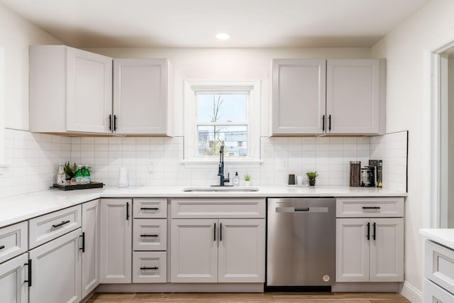 kitchen with white cabinetry, dishwasher, sink, backsplash, and light hardwood / wood-style floors