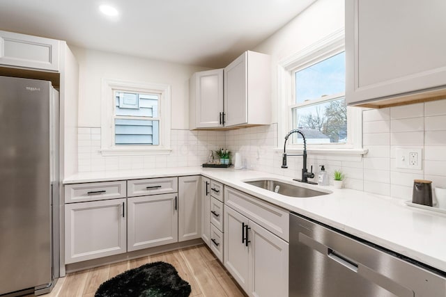 kitchen with white cabinets, sink, stainless steel appliances, and a wealth of natural light