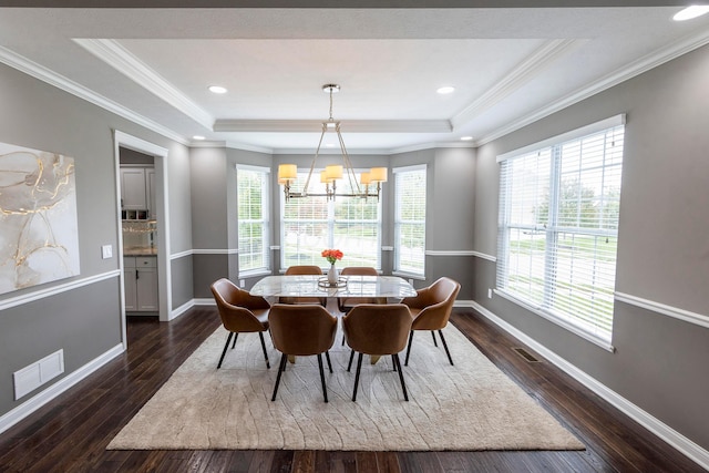 dining area featuring a chandelier, dark hardwood / wood-style flooring, a tray ceiling, and a wealth of natural light