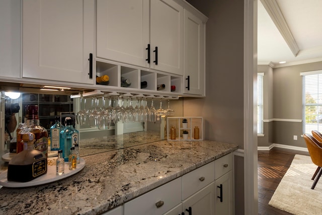 bar featuring light stone counters, dark hardwood / wood-style flooring, white cabinets, and ornamental molding