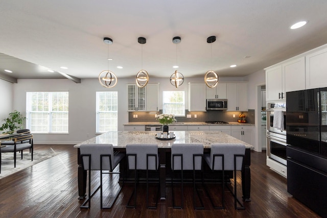 kitchen with white cabinets, stainless steel appliances, a kitchen island, and a wealth of natural light