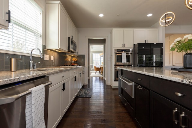 kitchen with dark hardwood / wood-style flooring, stainless steel appliances, white cabinetry, and a healthy amount of sunlight