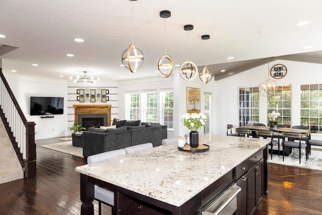 kitchen featuring decorative light fixtures, a kitchen island, dark hardwood / wood-style floors, and vaulted ceiling