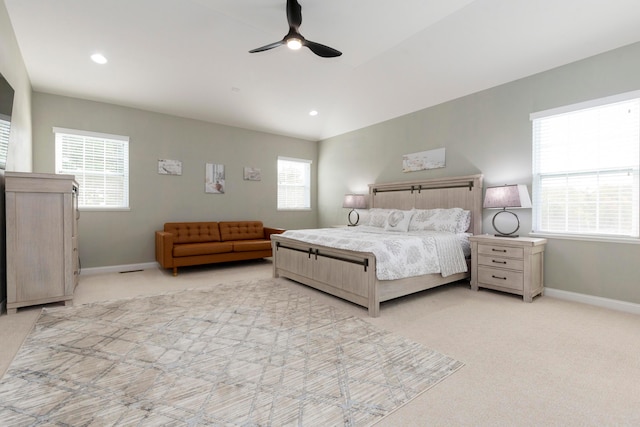 bedroom with ceiling fan, vaulted ceiling, light colored carpet, and multiple windows