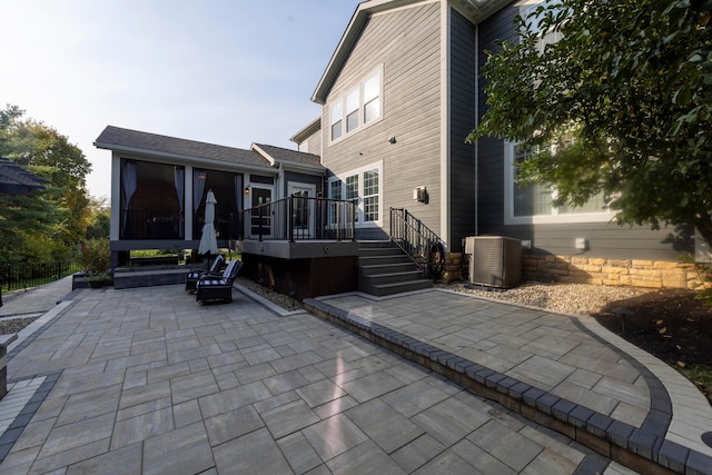 rear view of house featuring a wooden deck, a sunroom, a patio, and central AC unit