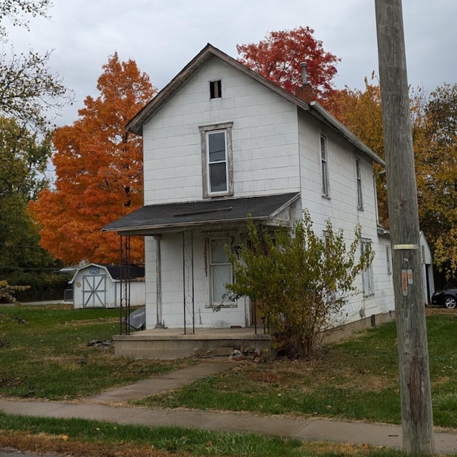 view of front of home with a front lawn, covered porch, and a storage unit