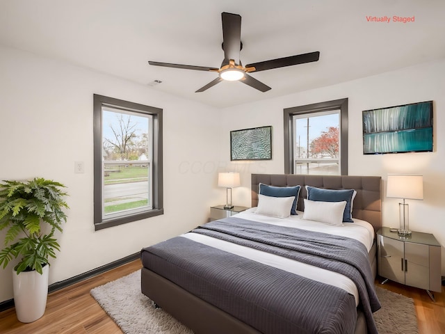 bedroom featuring light wood-type flooring, multiple windows, and ceiling fan